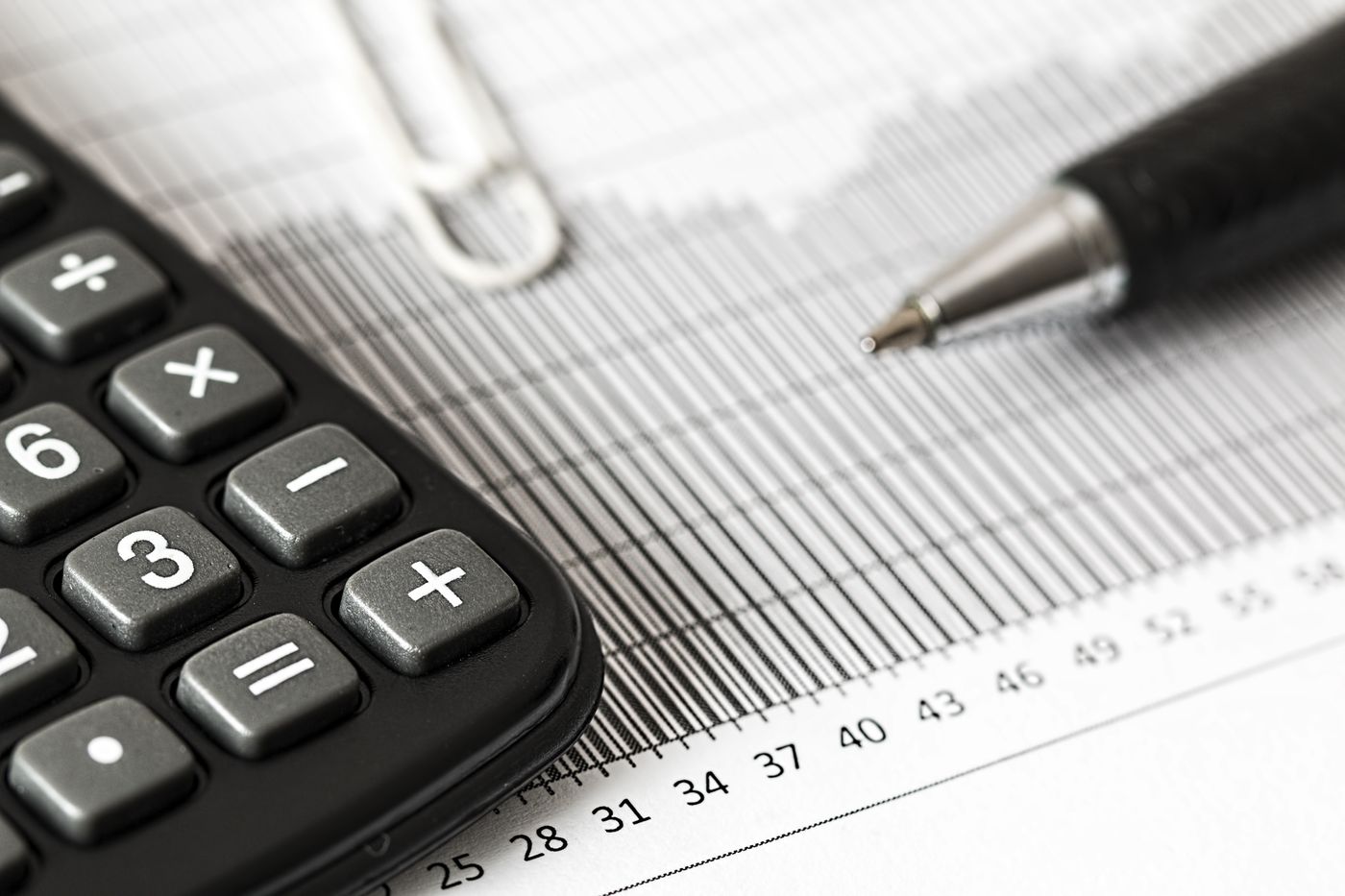 Calculatrice et stylo posés sur des graphiques financiers